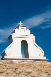 Low angle view of cross on building against sky
