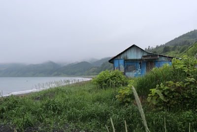 House by plants and mountains against sky