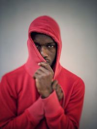 Portrait of young man wearing hood against gray background