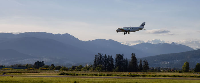 Airplane flying over field against sky