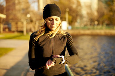 An athletic woman checking her run stats on her smart watch.
