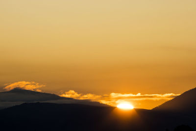 Scenic view of silhouette mountains against romantic sky at sunset