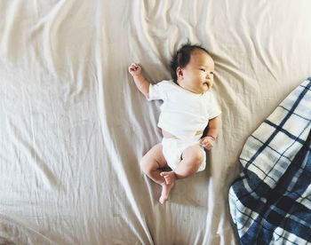 High angle view of cute baby lying on bed at home