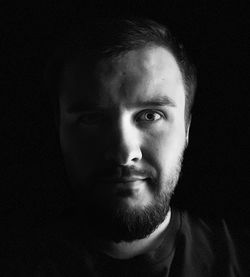 Close-up portrait of young man against black background