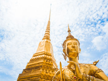 Low angle view of buddha statue by temple against sky