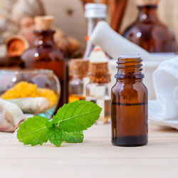 Close-up of herb and bottle on wooden table