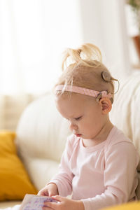 Side view of cute baby girl sitting on bed at home