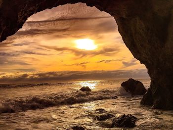 Natural arch by sea during sunset