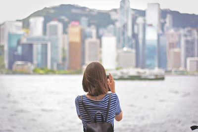 Rear view of woman photographing harbor