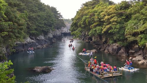 People on boat in river against trees