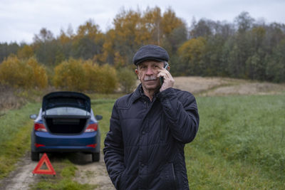 Man standing by car on land