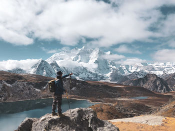 Rear view of person standing on rock against sky