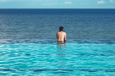 Rear view of shirtless man looking at sea