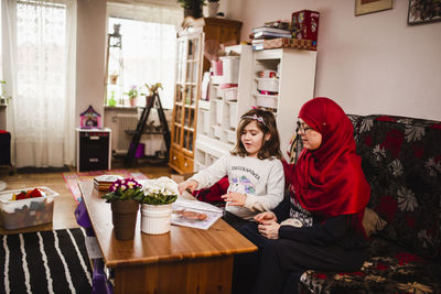 Mother with daughter sitting on sofa