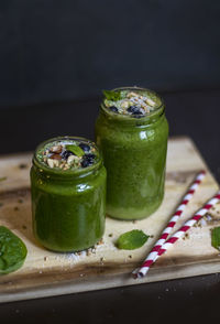 Close-up of green drink in jars on wood against black background