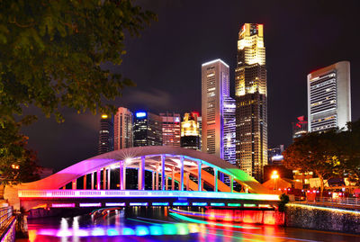 Illuminated bridge with tall buildings at night