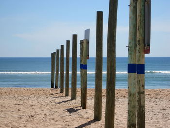 Wooden posts on beach against sky