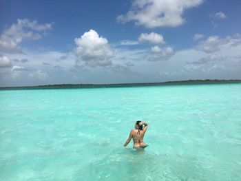 Rear view of woman standing in sea against sky