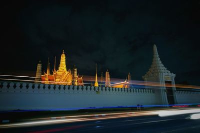 Light trails over street by wat phra kaeo against sky at night