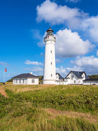 Lighthouse on field against sky