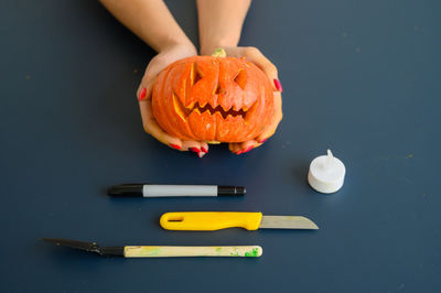 High angle view of hand holding pumpkin against black background