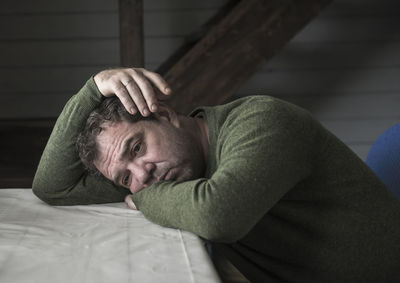 Close-up of sad man leaning on table