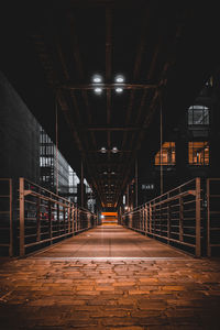 Empty footbridge in illuminated building at night