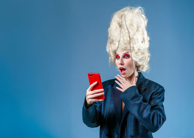 Young woman using mobile phone against blue background
