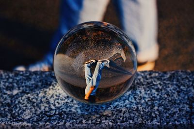 Reflection of man walking on road in crystal ball