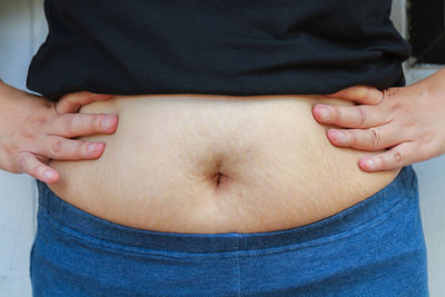 Midsection of pregnant woman touching abdomen