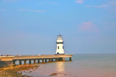 Lighthouse by sea against sky