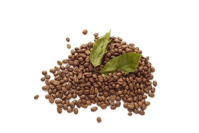 Close-up of coffee beans with leaves on white background