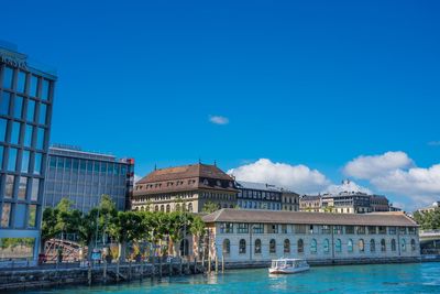 View of buildings at waterfront against blue sky