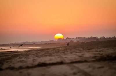 Scenic view of beach against orange sky