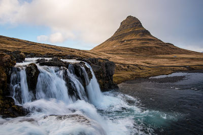 Scenic view of waterfall against sky