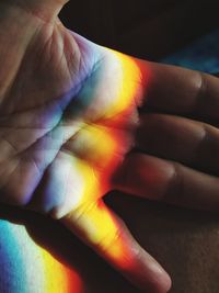 High angle view of multi colored light falling on hand
