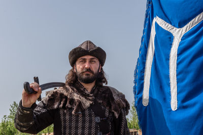 Portrait of man standing against blue sky