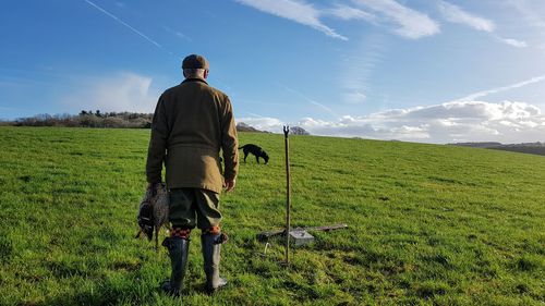 Full length rear view of man standing on field against sky