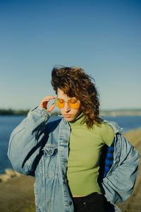 Young woman standing at beach against clear sky