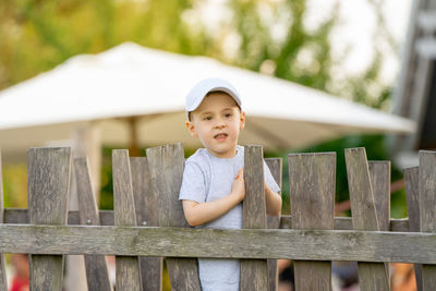 Portrait of boy standing by fence