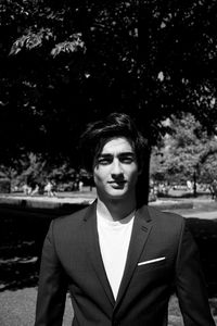 Portrait of young man standing against trees