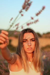 Portrait of beautiful young woman looking ahead holding lavender flowers