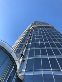 Low angle view of glass building against clear blue sky