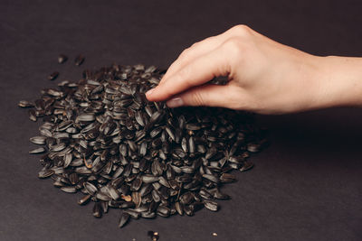 Close-up of hand holding coffee beans against black background
