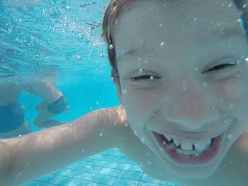 Close-up of cheerful boy swimming in pool
