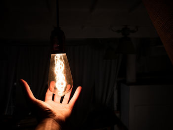 Close-up of hand holding illuminated light bulb