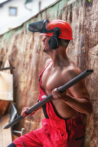 Man holding rod while standing against wall