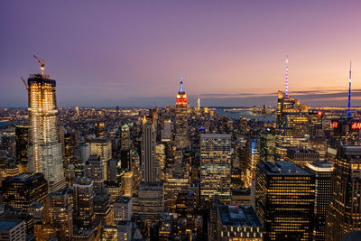 Illuminated buildings in city against sky during sunset