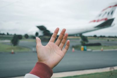 Close-up of person hand against sky