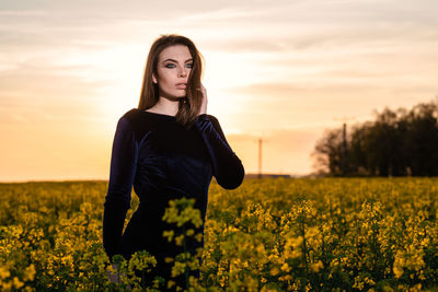 Portrait of beautiful young woman standing on field